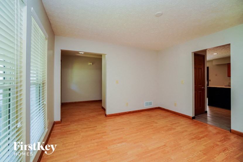 an empty living room with wood flooring and a door to a bedroom