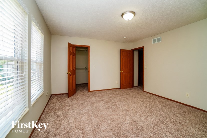 a bedroom with a large window and a door to a closet