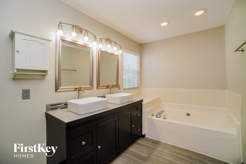 a bathroom with two sinks and a tub and a mirror