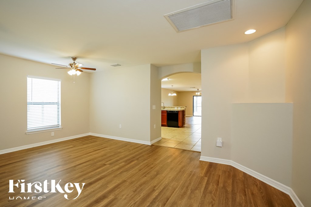 A spacious room with wooden floors and a ceiling fan.