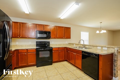 A kitchen with brown cabinets and black appliances.
