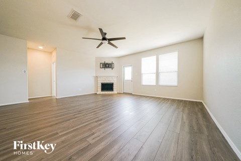 an empty living room with a ceiling fan and a fireplace