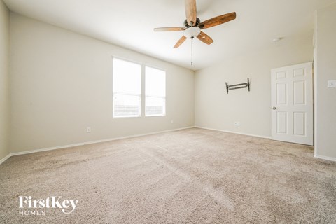 a spacious living room with carpet and a ceiling fan
