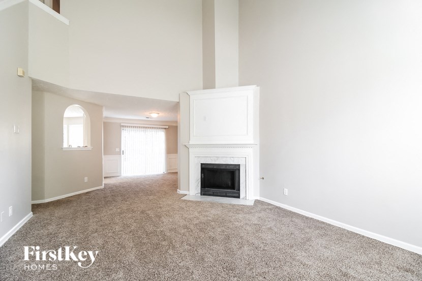 A large, empty room with a fireplace and a carpeted floor.