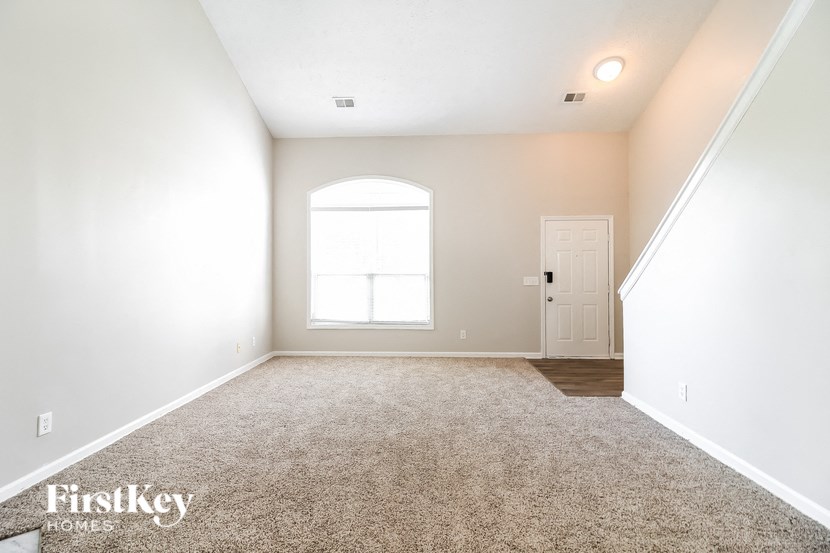 A room with a carpeted floor, a door, and a window.