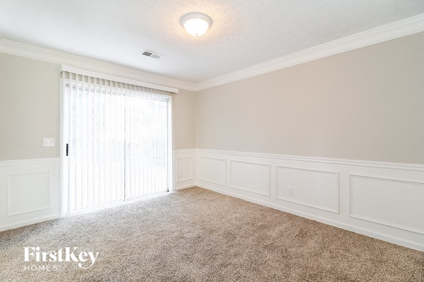 A room with a carpeted floor and a window with curtains.
