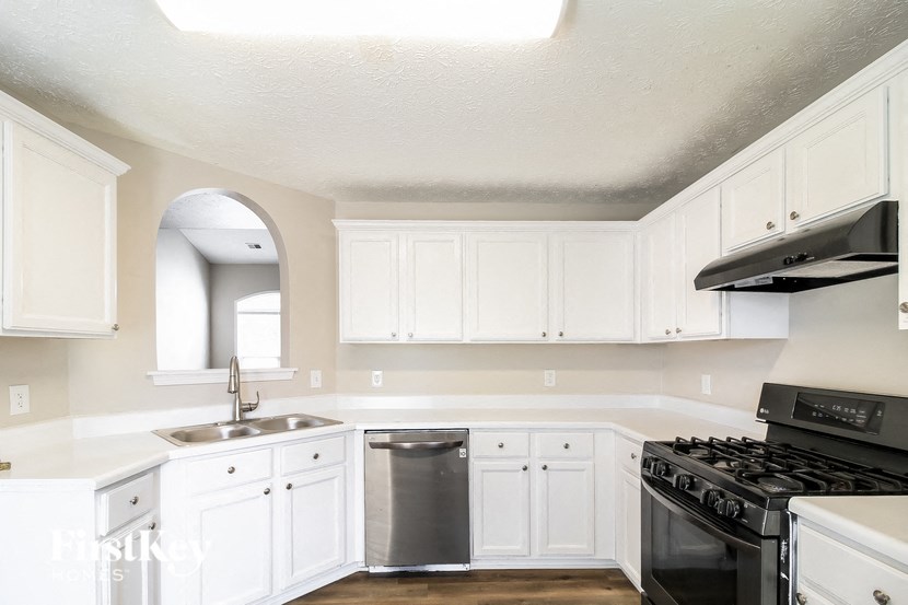 A kitchen with white cabinets and a black stove top oven.
