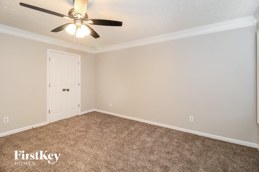 A room with a carpeted floor and a ceiling fan.
