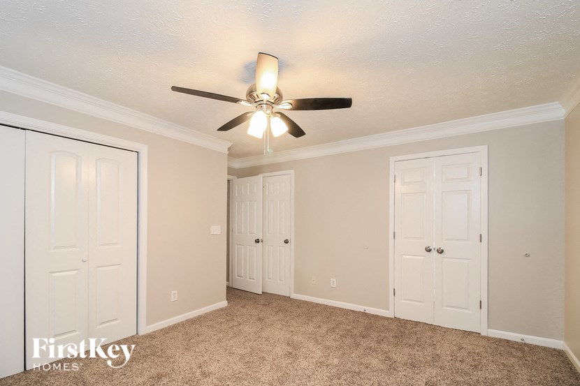 A room with a ceiling fan and carpeted floor.