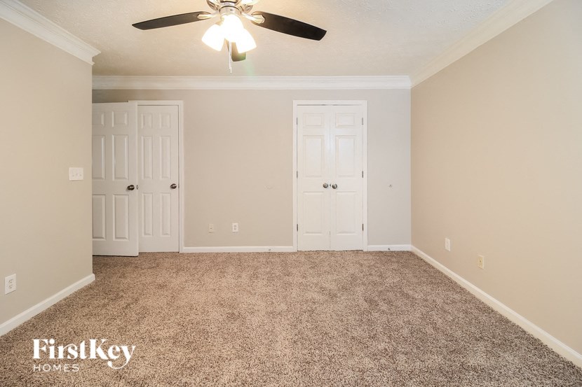 A room with a carpeted floor and a ceiling fan.
