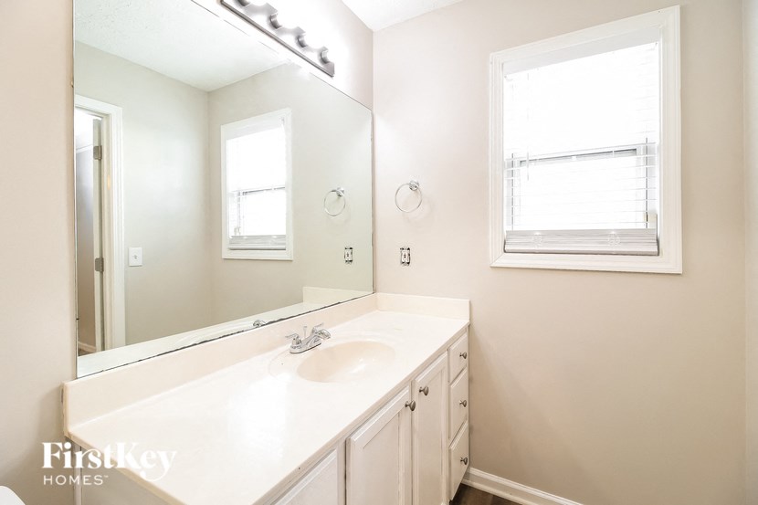 A bathroom with a sink, mirror, and a window.