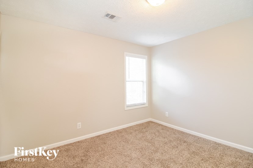 A room with a carpeted floor and a window letting in sunlight.