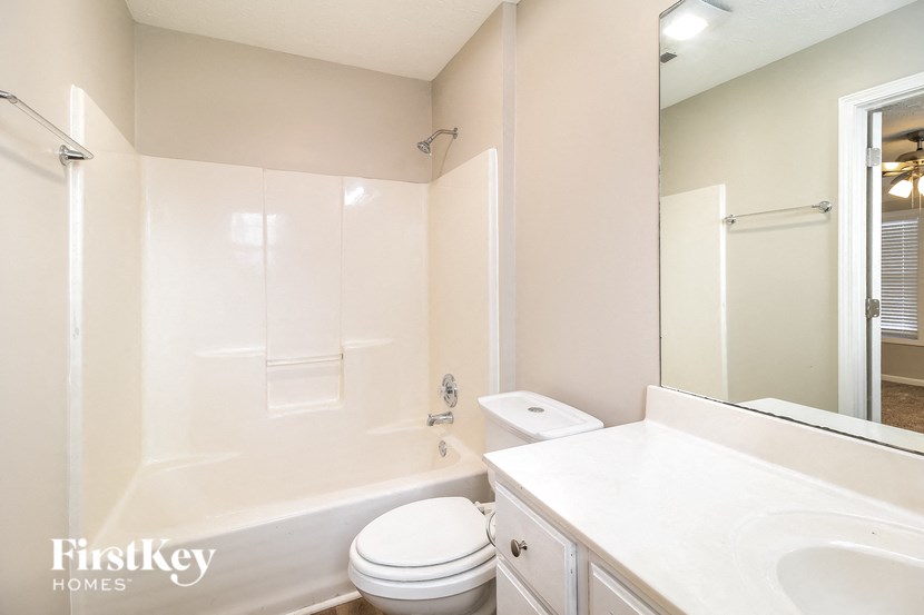 A white bathroom with a toilet, sink, and shower.