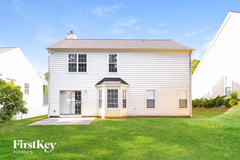 A white house with a black roof and a sign that says "FirstKey Homes".