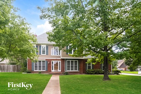 a house with a lawn and trees in front of it