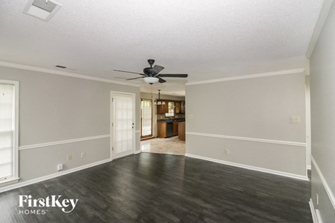 an empty living room with wood floors and a ceiling fan