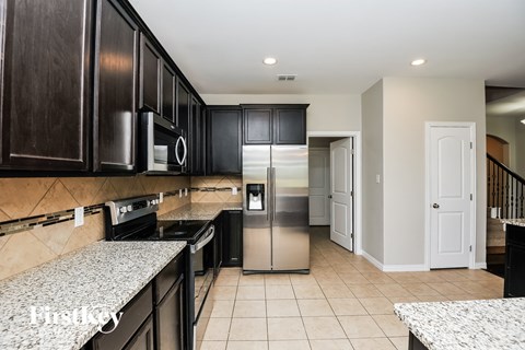 A kitchen with black cabinets and a stainless steel refrigerator.