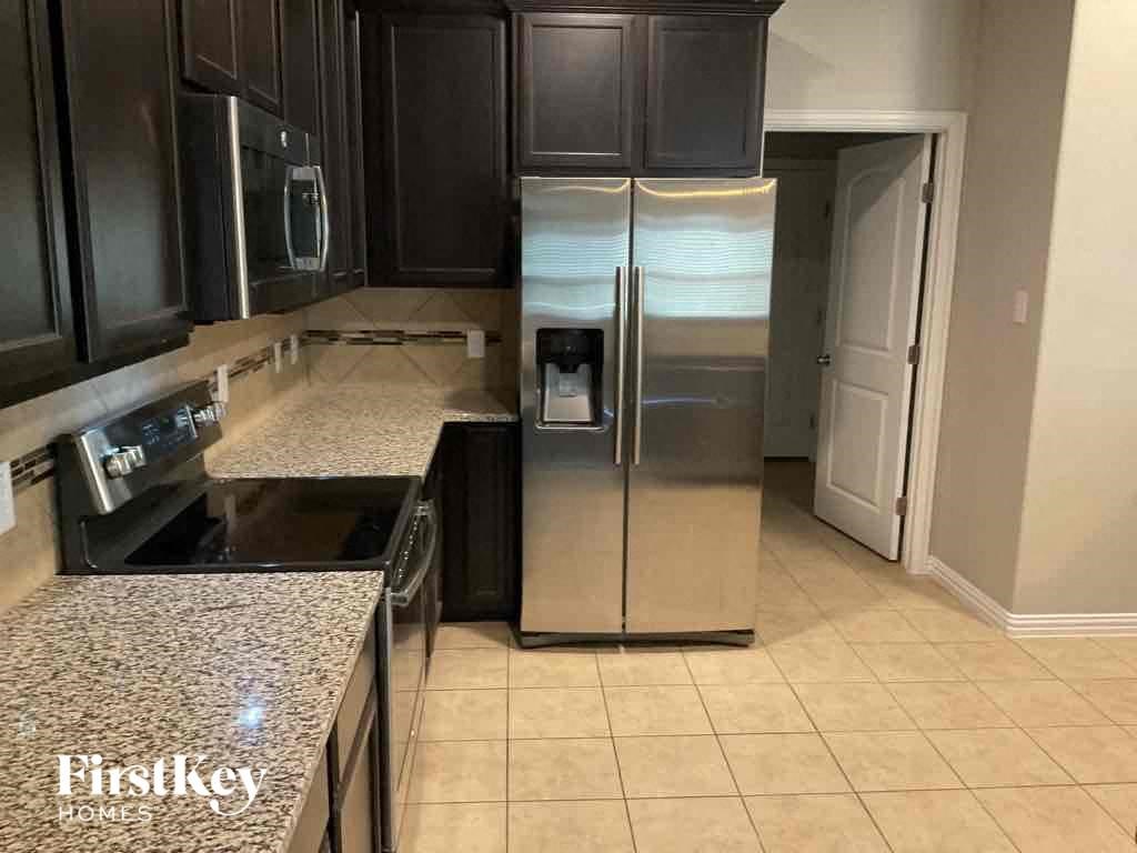 A kitchen with a granite countertop and a stainless steel refrigerator.