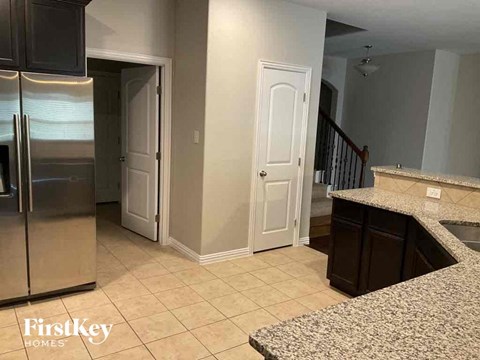 A kitchen with a granite counter top and a stainless steel refrigerator.