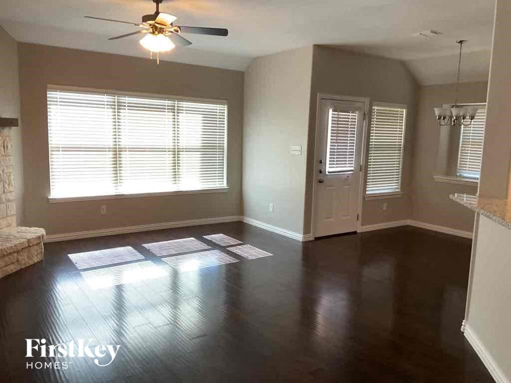 A spacious room with a ceiling fan and wooden flooring.