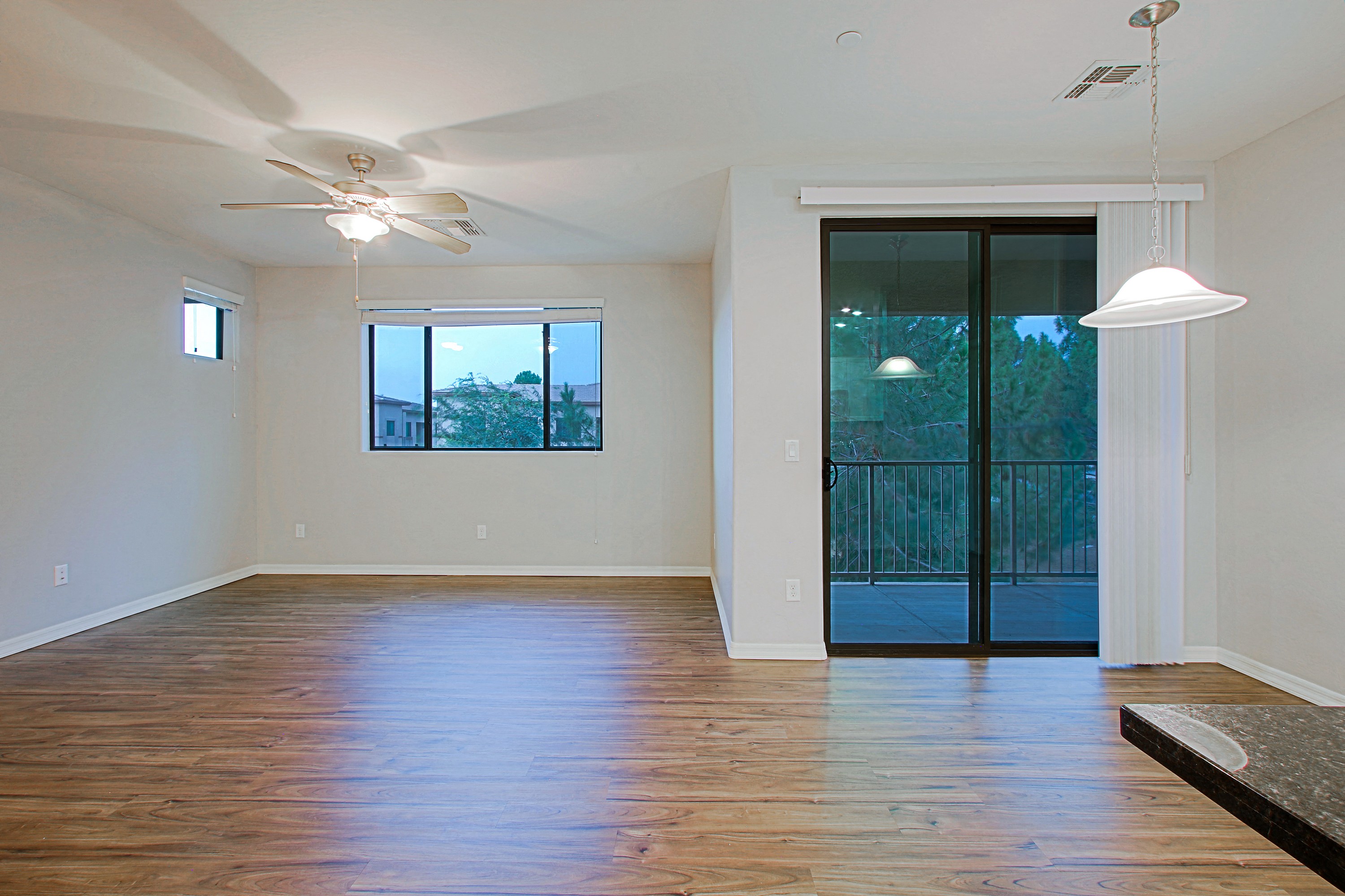 an empty living room with a sliding glass door to a balcony