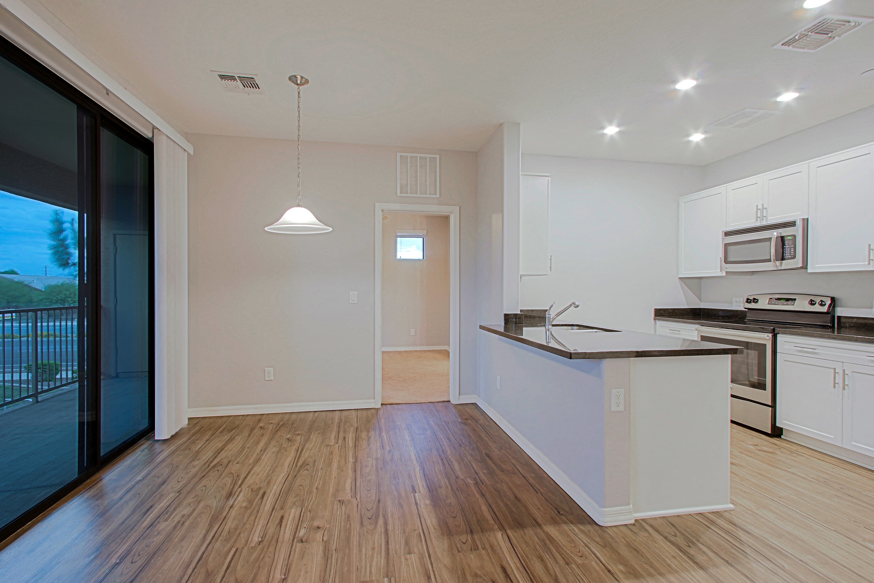 an empty kitchen with an island and a door to a balcony