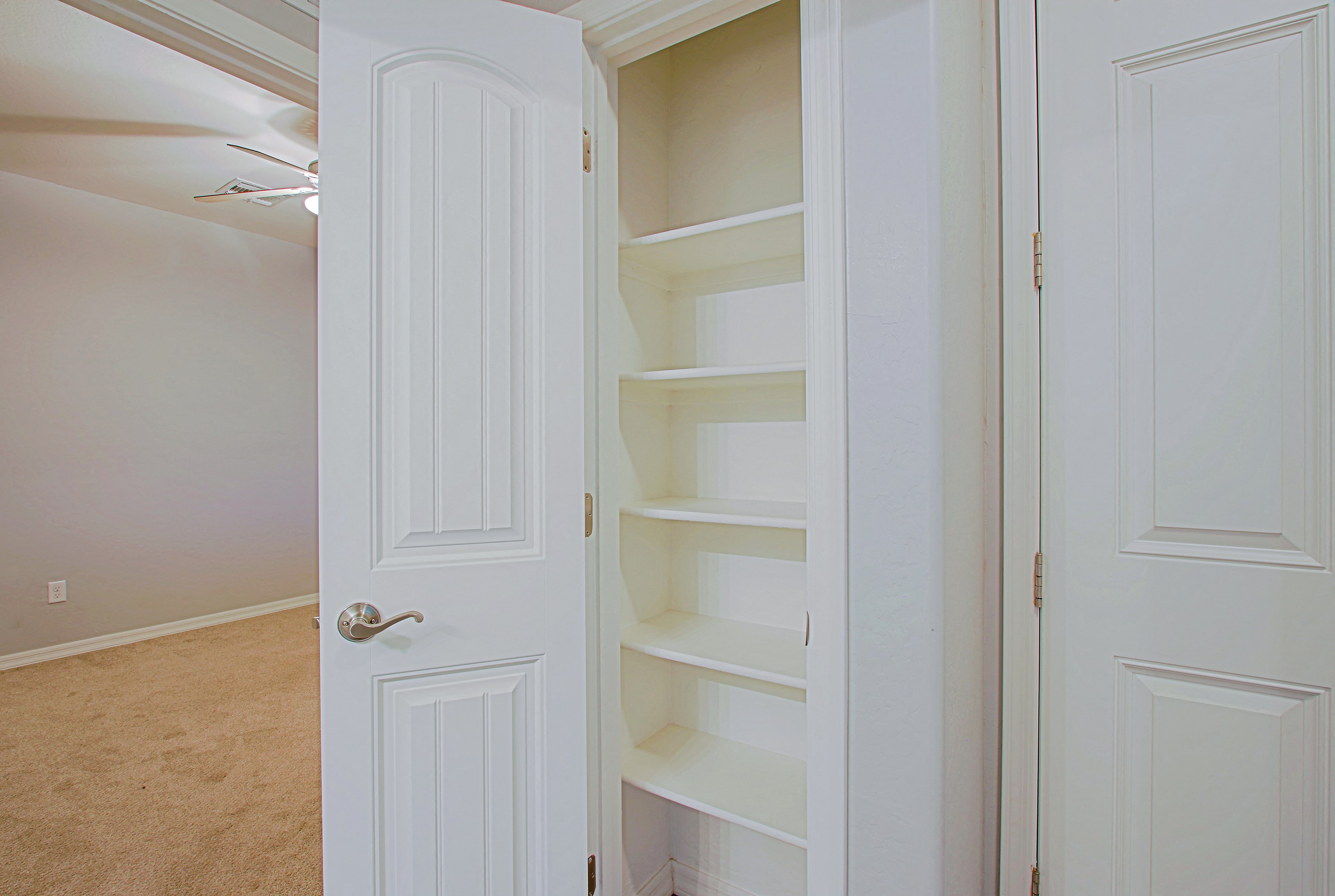 a closet with white shelves and a white door