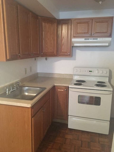 A white stove is in a kitchen with wooden cabinets.