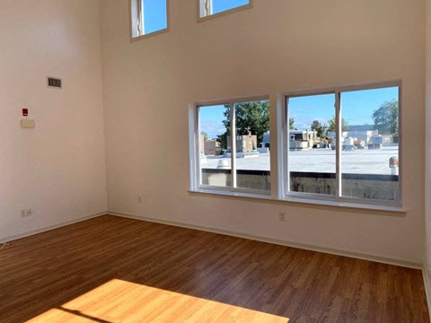 an empty living room with a wood floor and large windows