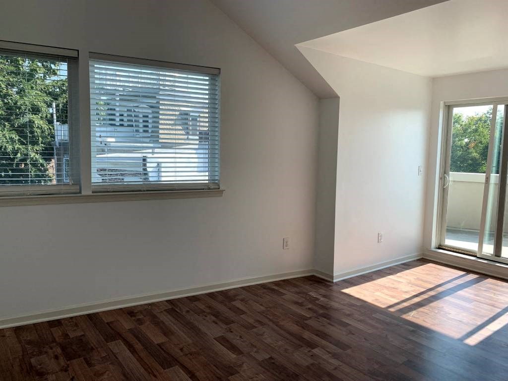 an empty living room with a window and wooden floors
