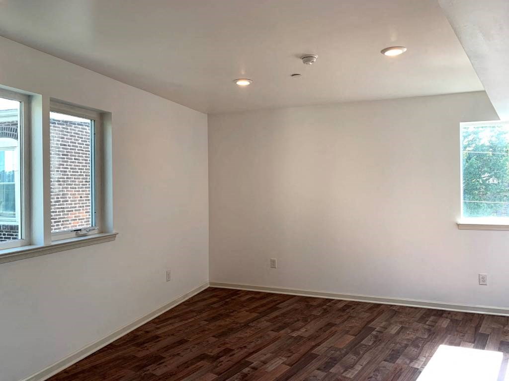 an empty living room with a hard wood floor and two windows