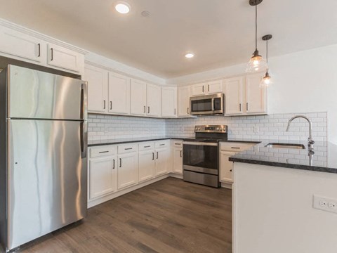 a kitchen with white cabinets and a stainless steel refrigerator