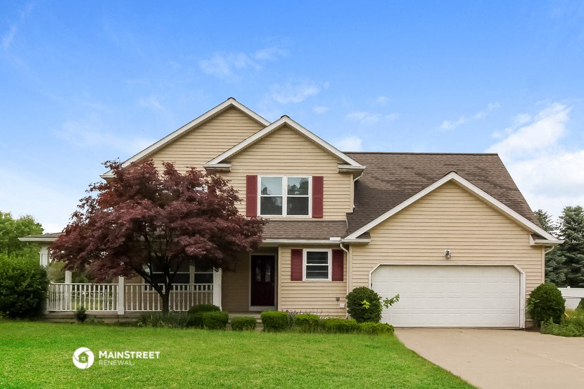 a tan house with red shutters and a white garage door