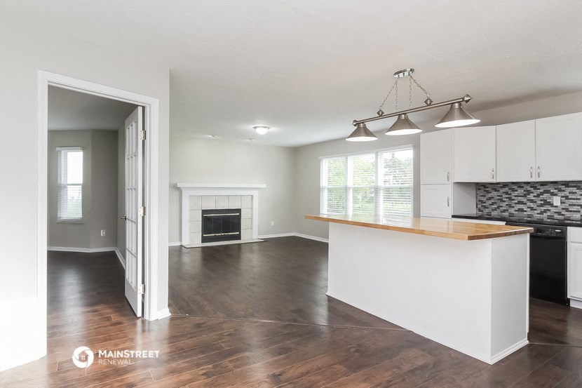 an open kitchen and living room with white cabinets and a fireplace