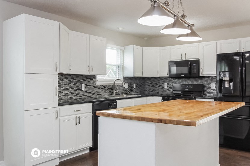 a white kitchen with black appliances and a butcher block counter top