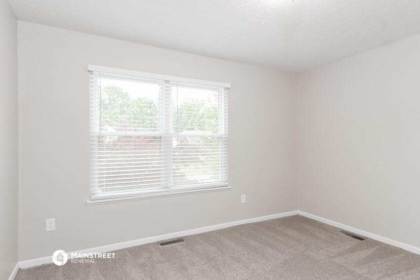 a bedroom with a large window and a carpeted floor