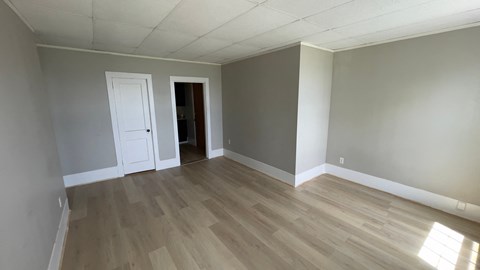 an empty living room with gray walls and wooden floors