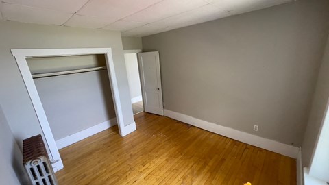 a bedroom with a closet and a hard wood floor