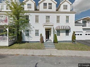 the front of a white house with a sidewalk