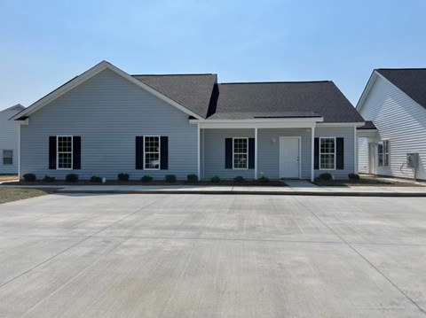 A white house with a grey roof and a driveway in front.