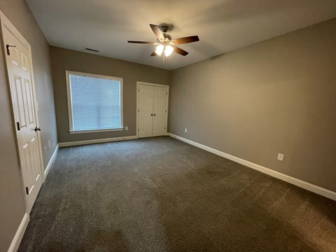 A room with a ceiling fan and carpeted floor.