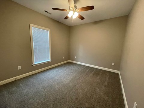 A room with a ceiling fan and a window with blinds.