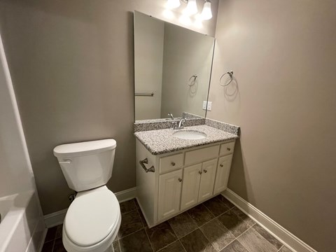 A bathroom with a toilet, sink, and mirror.
