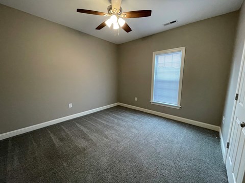 A room with a ceiling fan and a window.