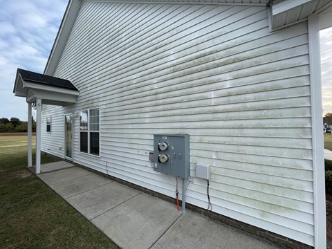 A white building with a grey electrical box on the side.