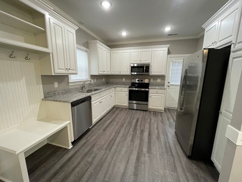A kitchen with white cabinets and a black refrigerator.