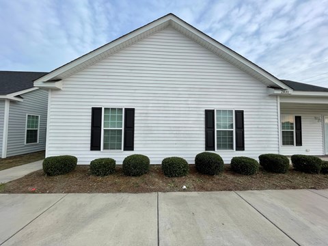 A white house with black shutters and a grey roof.