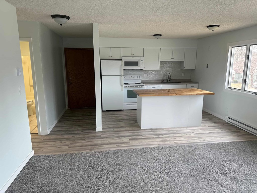 an empty kitchen with white cabinets and a counter top