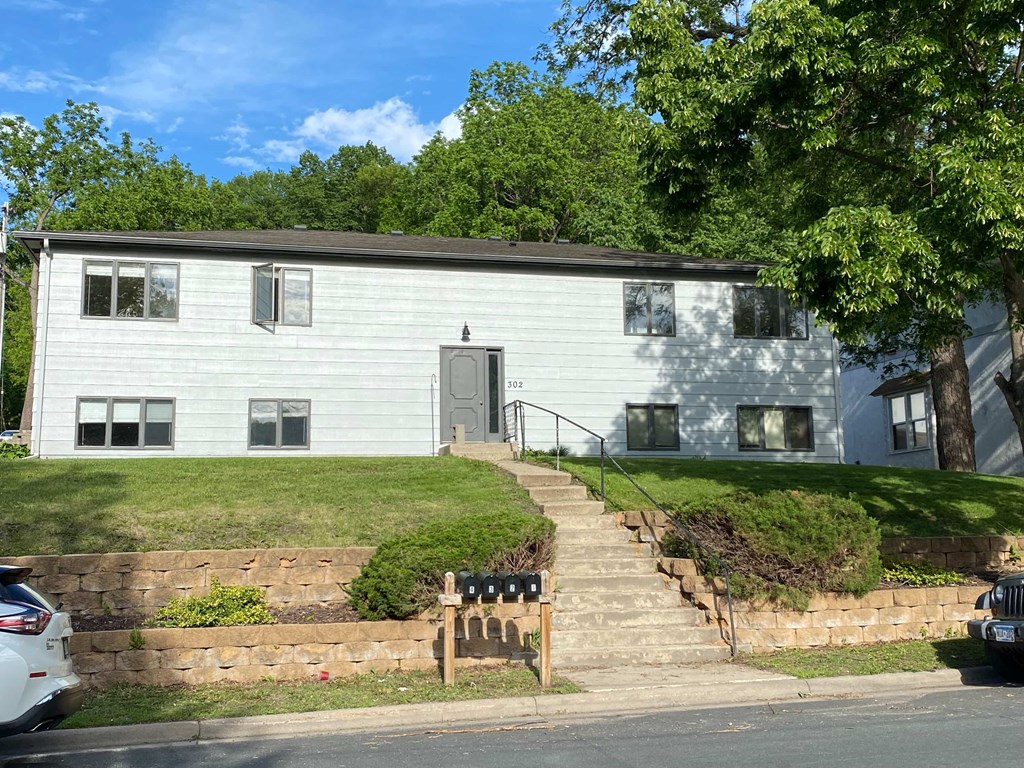 a white house with stairs and a bench in front of it