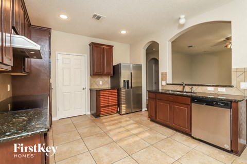 A kitchen with a tile floor and a refrigerator with orange storage boxes behind it.